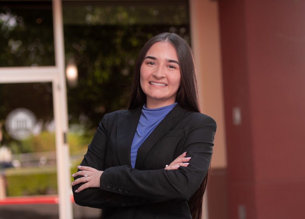 woman in blazer with arms crossed in front of building