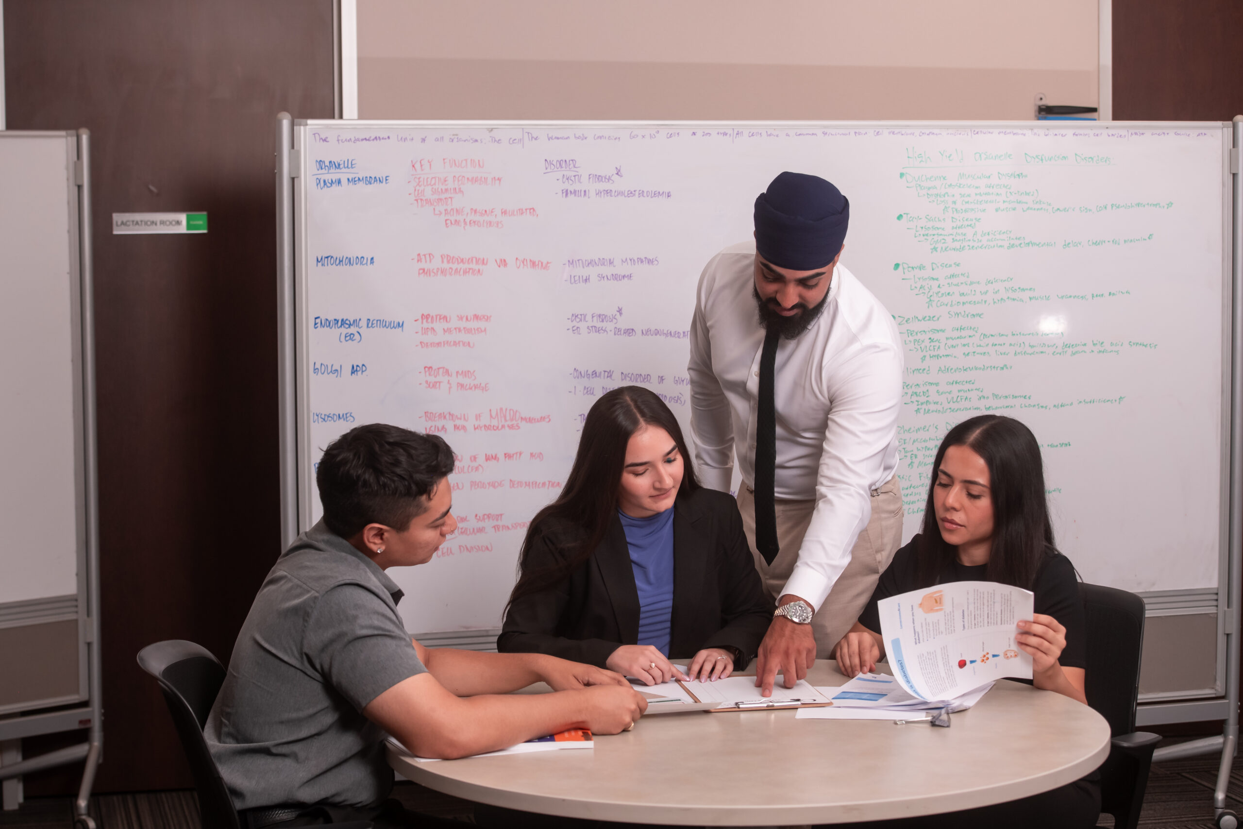 Group of students studying at table in front of white board