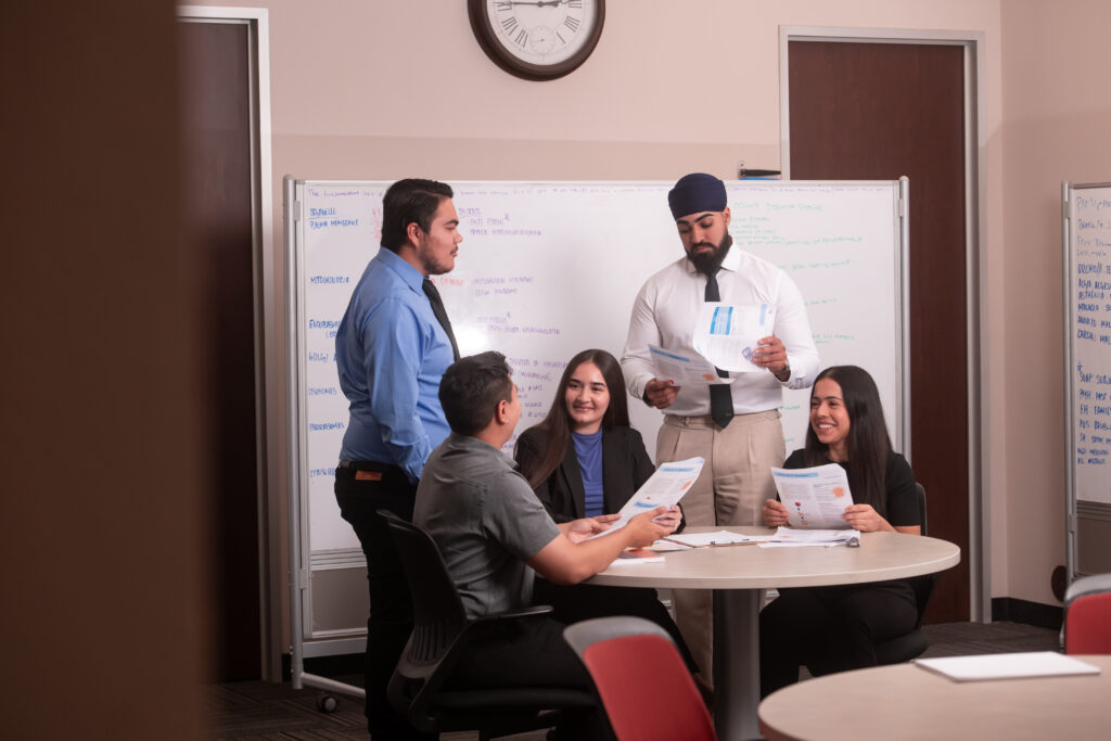 5 people studying at table and white board