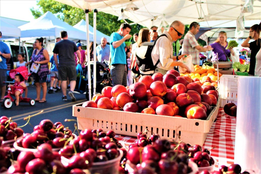 cherries and stone fruit in baskets under tent with people walking by